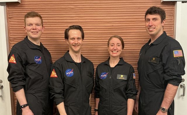 Los cuatro voluntarios de la segunda misión CHAPEA sonríen frente a una pared impresa en 3D dentro del hábitat del Centro Espacial Johnson