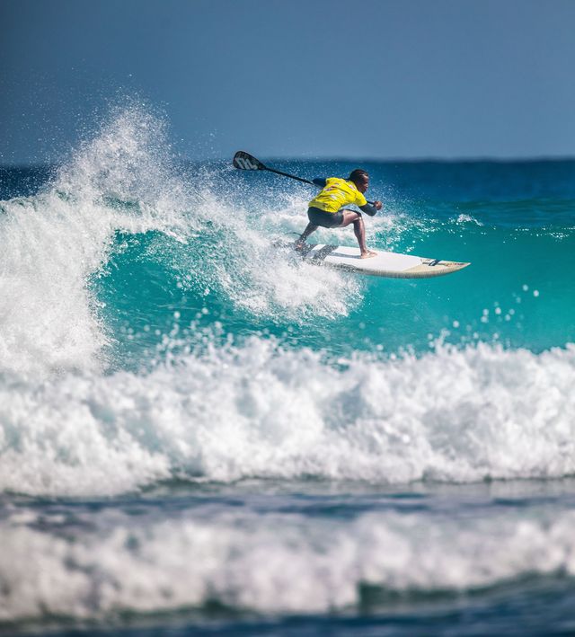 Un competidor de stand-up paddle surfea una ola