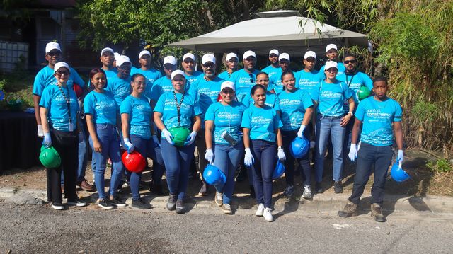 Voluntarios de Reid & Compañía y Autocamiones con cascos y camisetas azules de Hábitat para la Humanidad en Dubó, San Cristóbal