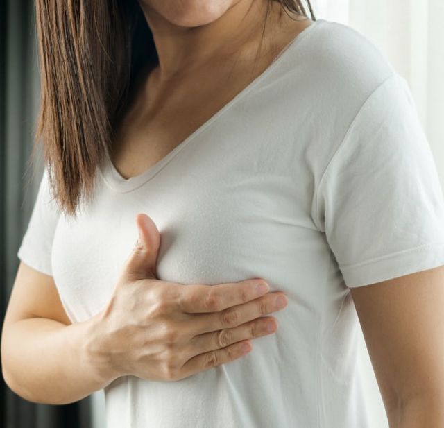 Una mujer con camiseta blanca se lleva la mano al pecho