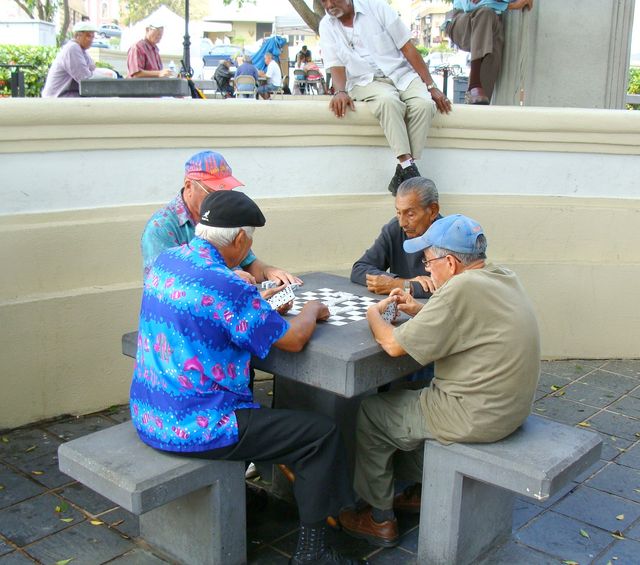 Cuatro hombres juegan una partida de dominó en una mesa al aire libre en San Juan, Puerto Rico