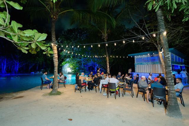 Mesas de cena al aire libre junto a una piscina iluminada en la selva