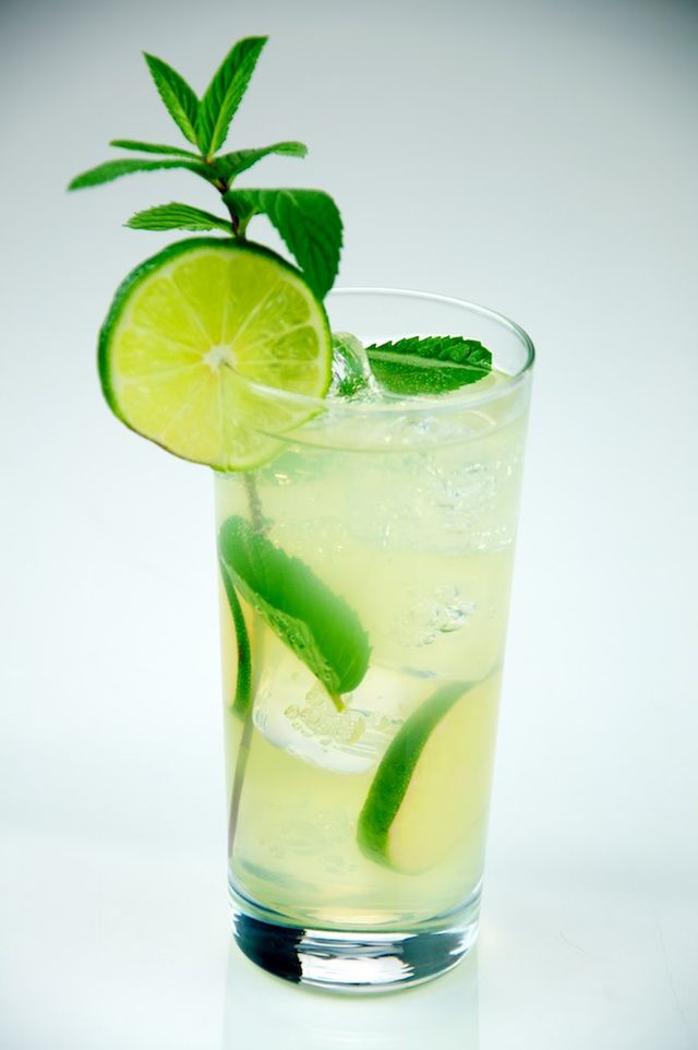 Vaso alto con ron, refresco de limón, hielo, rodaja de limón verde y hierbabuena