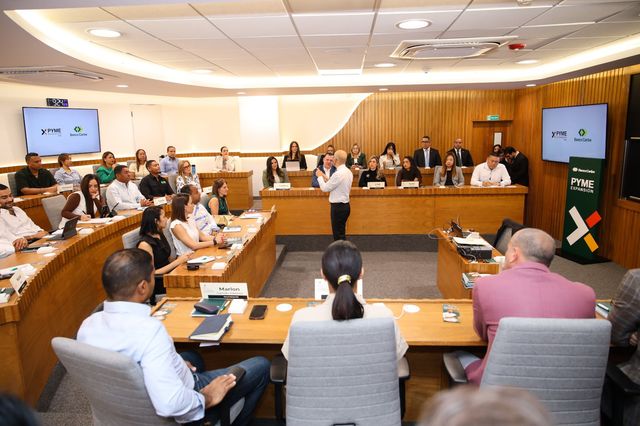 Empresarios siguen una capacitación de PYME Expansión con pantallas de Banco Caribe y BARNA al fondo