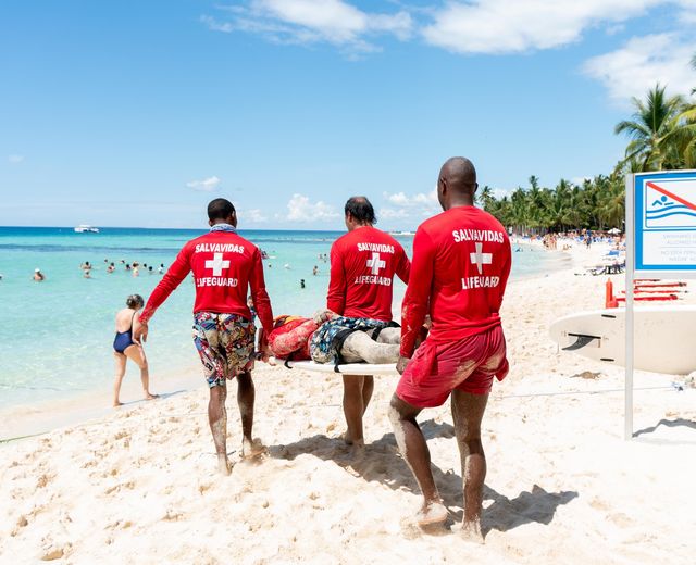Tres salvavidas trasladan una camilla por la playa