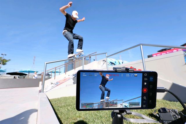 Un teléfono Galaxy en un trípode graba a un patinador que salta sobre una baranda