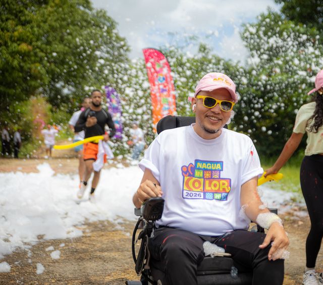 Un participante en silla de ruedas sonríe entre la espuma del recorrido