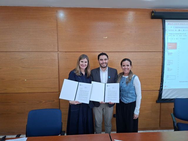 Tres participantes muestran documentos firmados durante el encuentro