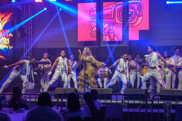 Miriam Cruz y sus bailarines con sombreros en plena coreografía, con la orquesta detrás