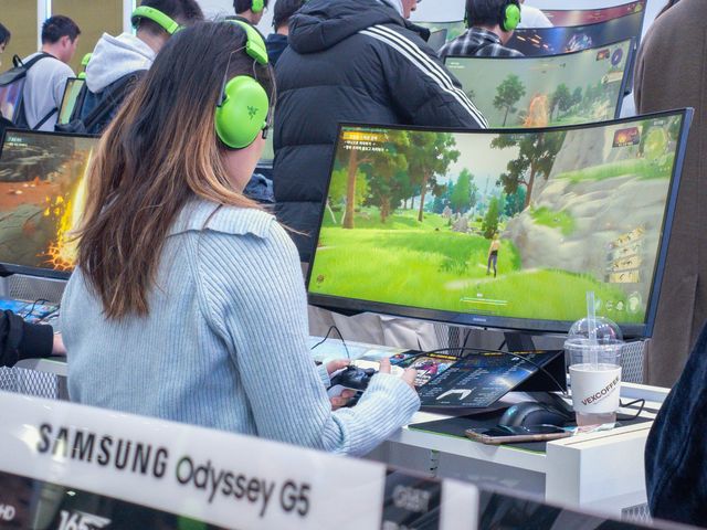 Jugadora con audífonos verdes juega frente a un monitor curvo Samsung Odyssey