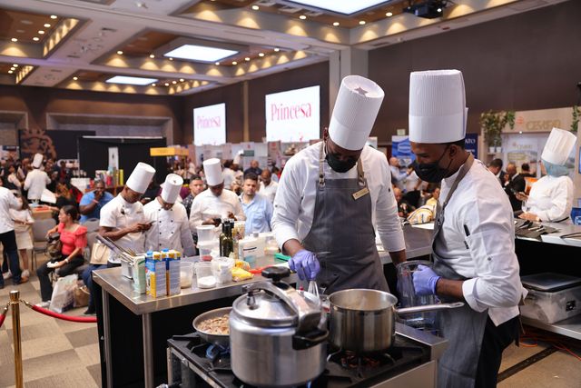 Chefs cocinan en estaciones durante una competencia culinaria