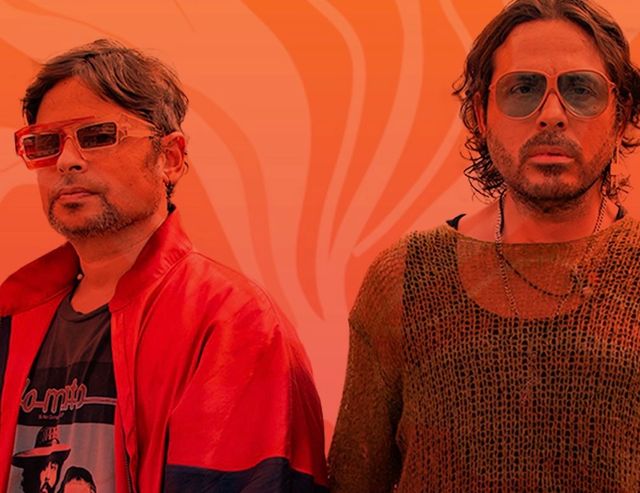 Servando y Florentino, con gafas de sol, sobre un fondo naranja