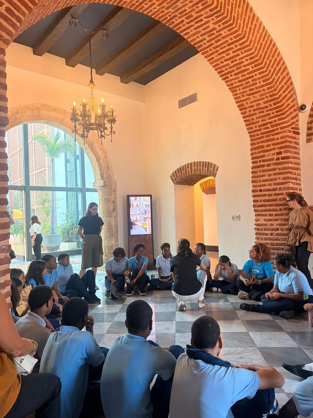 Estudiantes sentados en el suelo de una sala colonial durante una actividad en la Zona Colonial