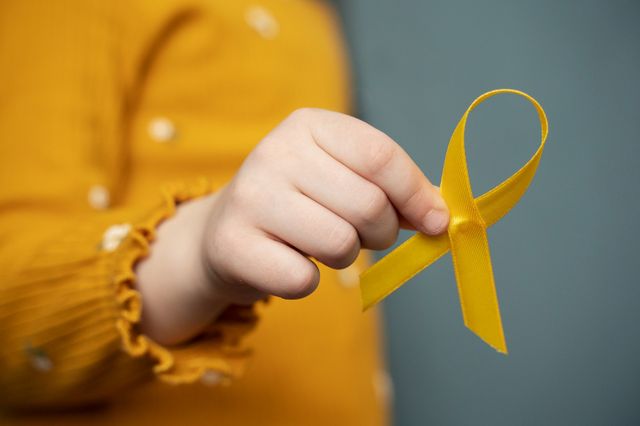 Una mano infantil sostiene un lazo dorado