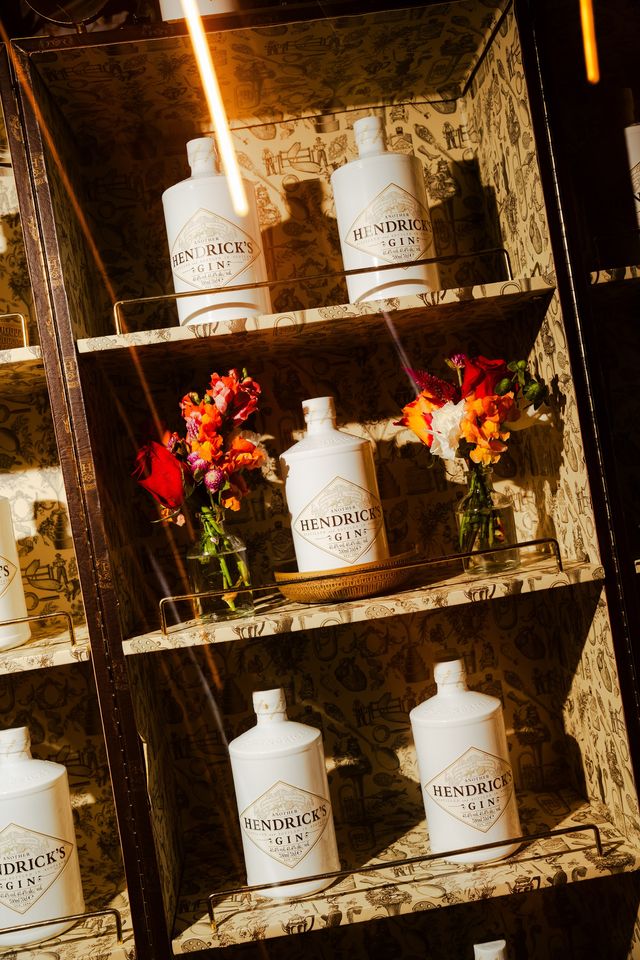 Botellas blancas de Another Hendrick's en una vitrina con flores