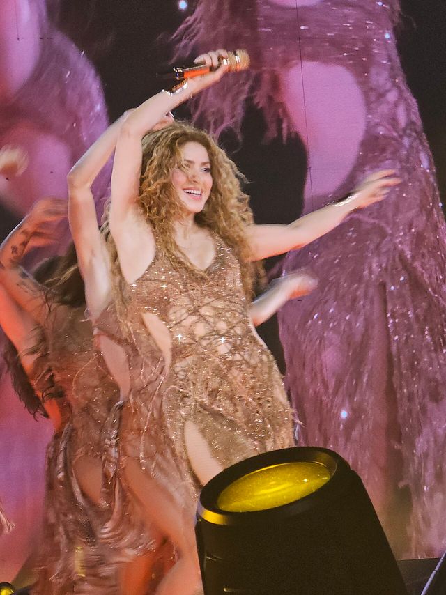 Shakira, con un vestido dorado de flecos, levanta el micrófono y baila en el escenario