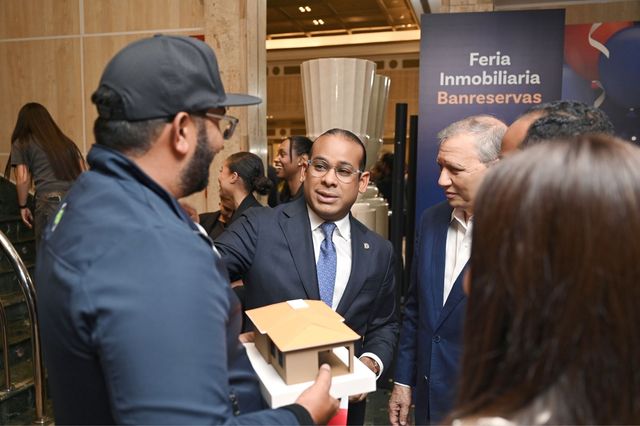 Wester Hernández conversa con asistentes mientras sostiene el galardón en la Feria Inmobiliaria Banreservas