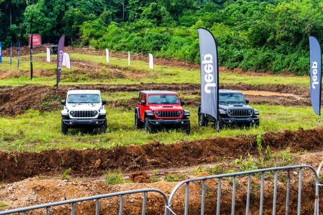 Tres Jeep Wrangler, blanco, rojo y gris, en exhibición junto al circuito de lodo de La War Off Road
