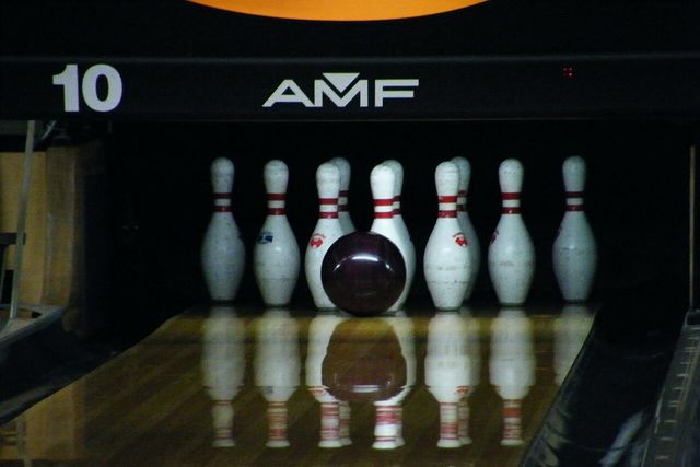 Una bola de boliche a punto de chocar con los pinos en una pista