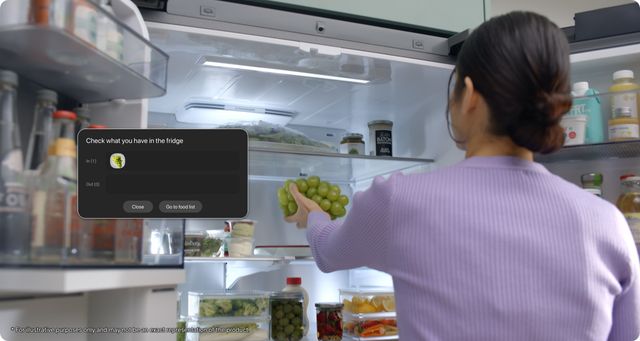 Una mujer guarda uvas en un refrigerador Samsung mientras la pantalla registra el alimento