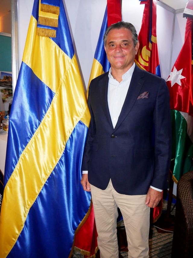 Juan Cordero, cónsul honorario de Suecia, junto a las banderas del Rincón Diplomático