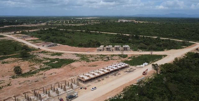 Viviendas y estructuras en obra junto a un camino de tierra en Larimar City & Resort