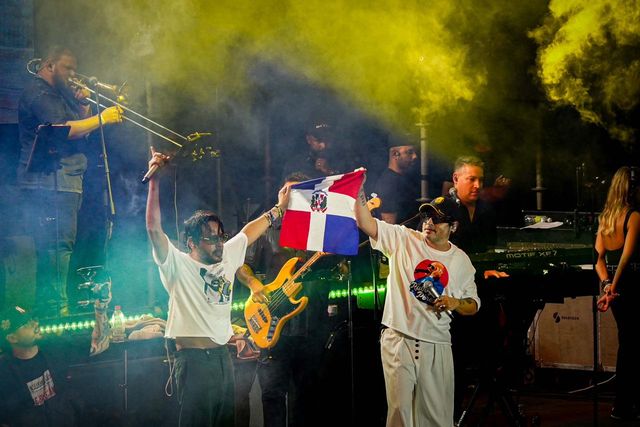 Servando y Florentino levantan una bandera dominicana en la tarima del Óvalo de la Feria Ganadera