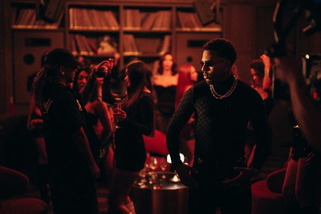 Myke Towers en una fiesta con luz roja en una escena de «Te Imagino»