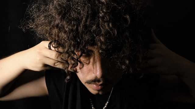 CHITU se lleva las manos al cabello en una sesión de fotos en penumbra