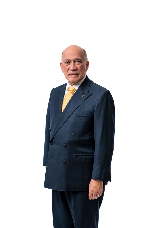 Luis Canela, de pie, con traje azul y corbata amarilla