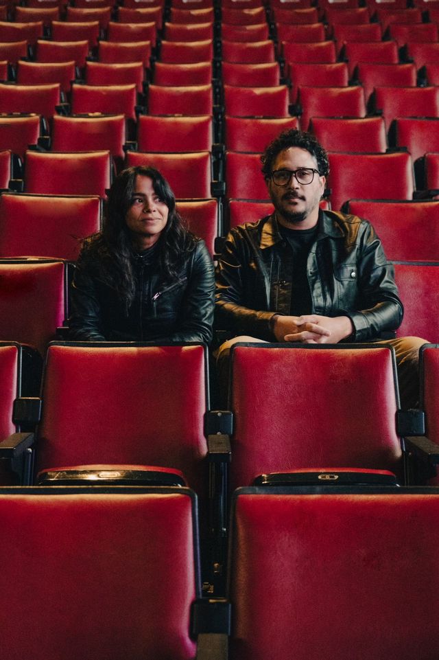 Los integrantes de MarteOvenus sentados entre butacas rojas de un teatro vacío