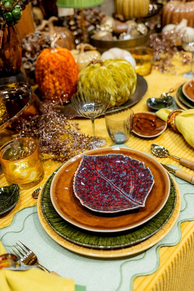 Mesa de otoño con platos de cerámica y calabazas decorativas