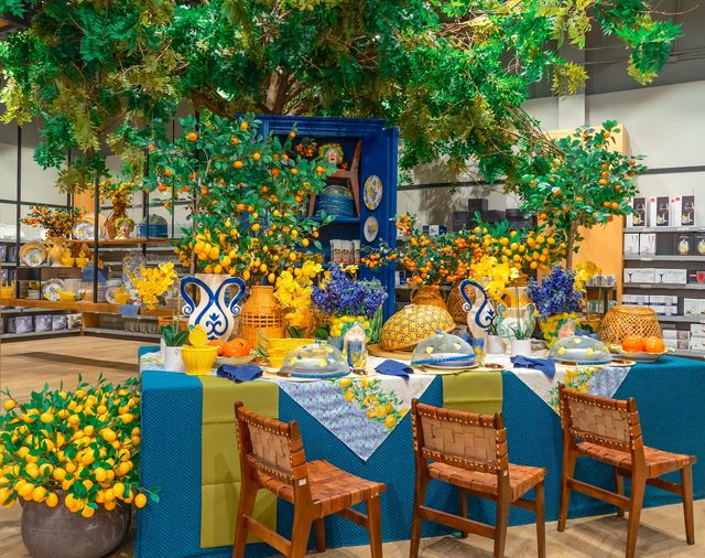 Mesa con mantel azul, vajilla estampada y arreglos de limones