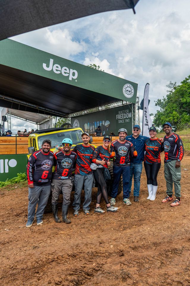 Pilotos con jerseys de competencia posan frente a un Jeep amarillo y la tarima de Jeep en la Finca Beatriz