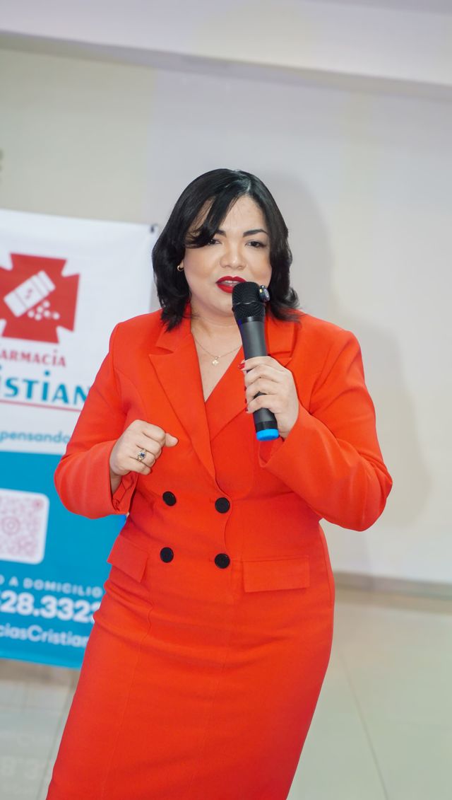 Una expositora habla con micrófono frente al banner de Farmacia Cristina