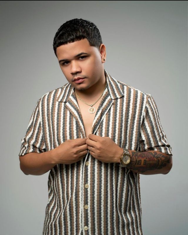 Raffy Martínez con camisa de rayas, abotonándose