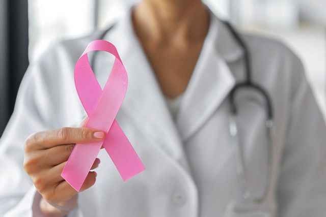 Una médica sostiene un lazo rosado de la lucha contra el cáncer de mama