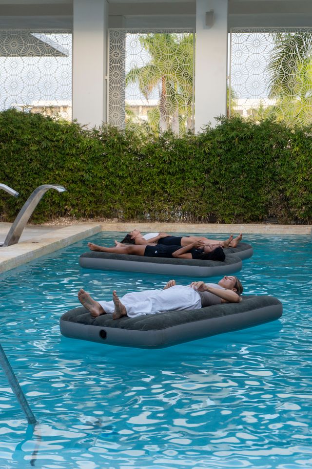 Invitados descansan sobre colchonetas flotantes en la piscina del spa
