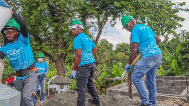 Voluntarios con cascos verdes trasladan materiales durante la jornada de Pisos para Jugar