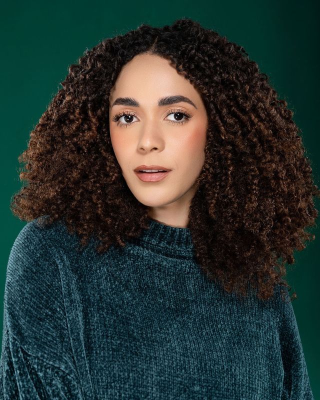 Lía Lockhart con suéter verde sobre fondo verde oscuro