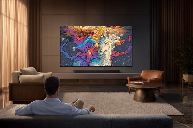 Un hombre contempla una obra de arte en un televisor Samsung Micro RGB colgado en la pared de una sala