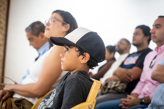 Asistentes, entre ellos un niño con gorra, siguen la presentación