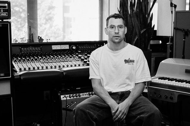 Jack Antonoff, con camiseta blanca y lentes, sentado frente a una consola de grabación en Electric Lady Studios en 2023