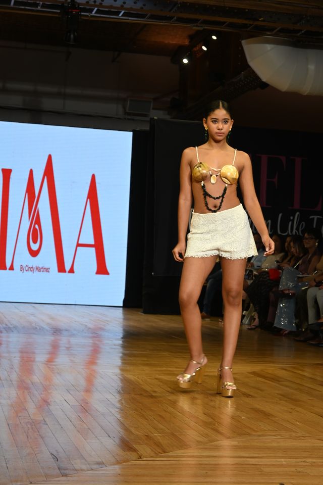 Modelo desfila con pieza de joyería de Cima frente al logo de The Fashion Life Tour