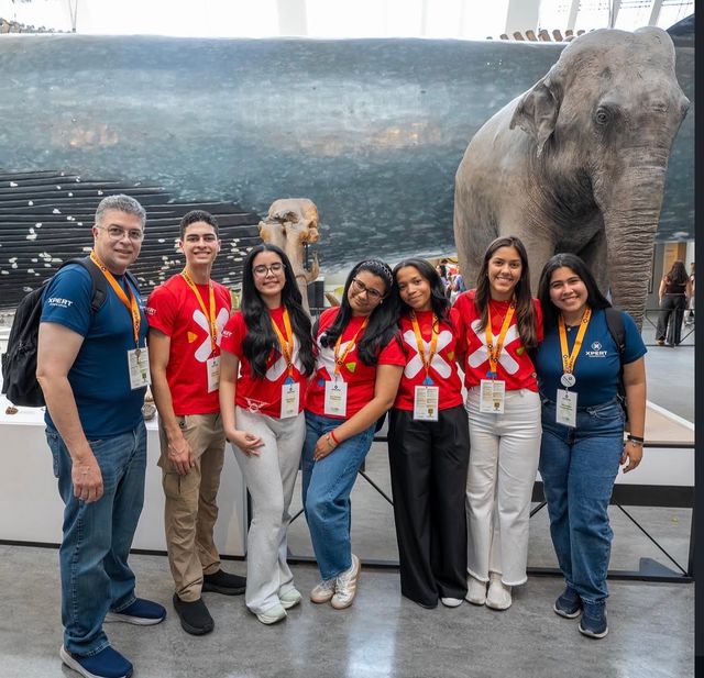 La delegación dominicana con sus supervisores junto a la figura de un elefante en un museo