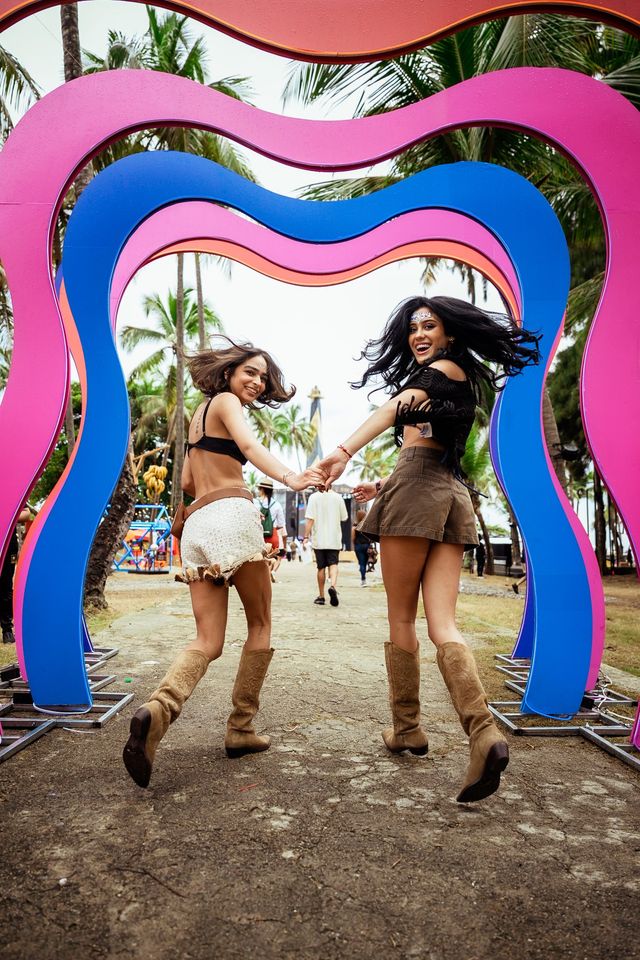 Dos asistentes cruzan de la mano un arco de colores en el festival Isle of Light en Santo Domingo