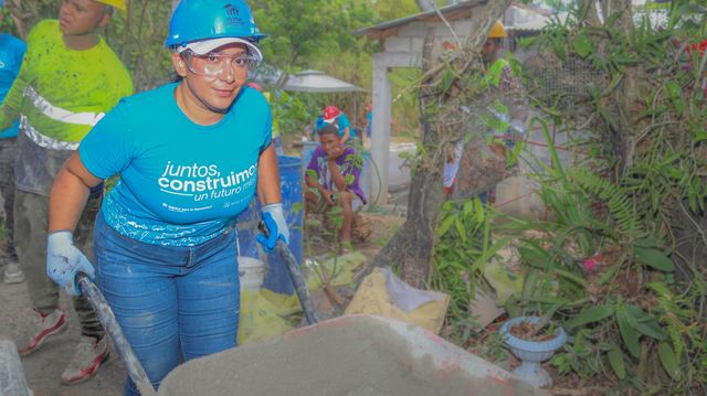 Una voluntaria empuja una carretilla con concreto en Dubó