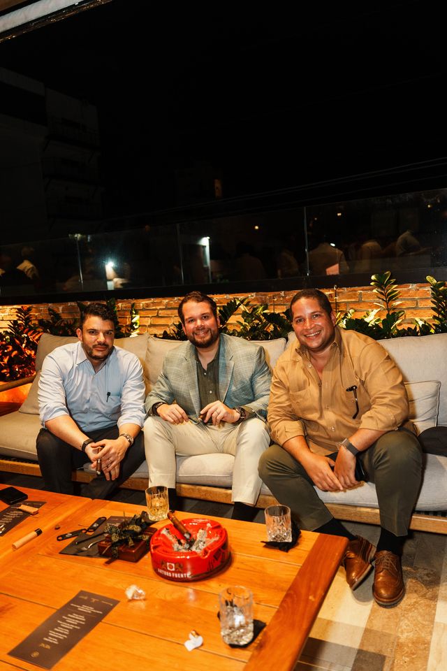 Carlos Pérez, Orlando Jorge y Jean Paul Valdez en un sofá junto a una mesa con cigarros