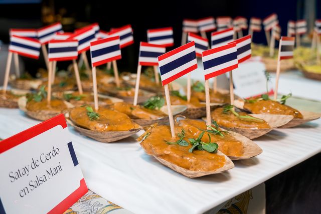 Satay de cerdo en salsa maní con banderitas de Tailandia en la degustación de la feria