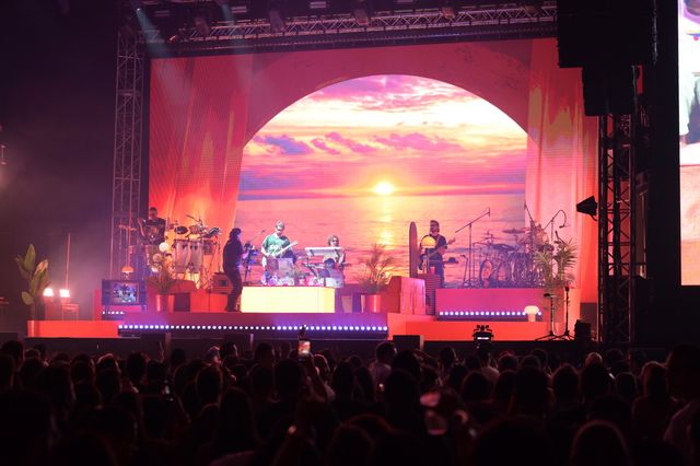Rawayana en la tarima de la Gran Arena del Cibao, con una escenografía de playa y atardecer